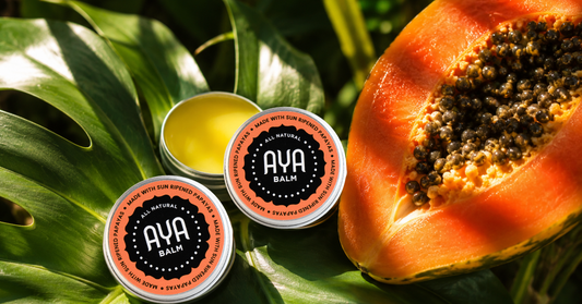 AYA Balm natural skincare tins with fresh papaya on tropical leaves - all natural petroleum-free balm made with sun ripened papayas, South Africa