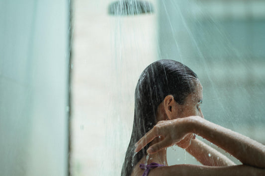 Woman standing under hot shower - what hot water really does to your skin barrier