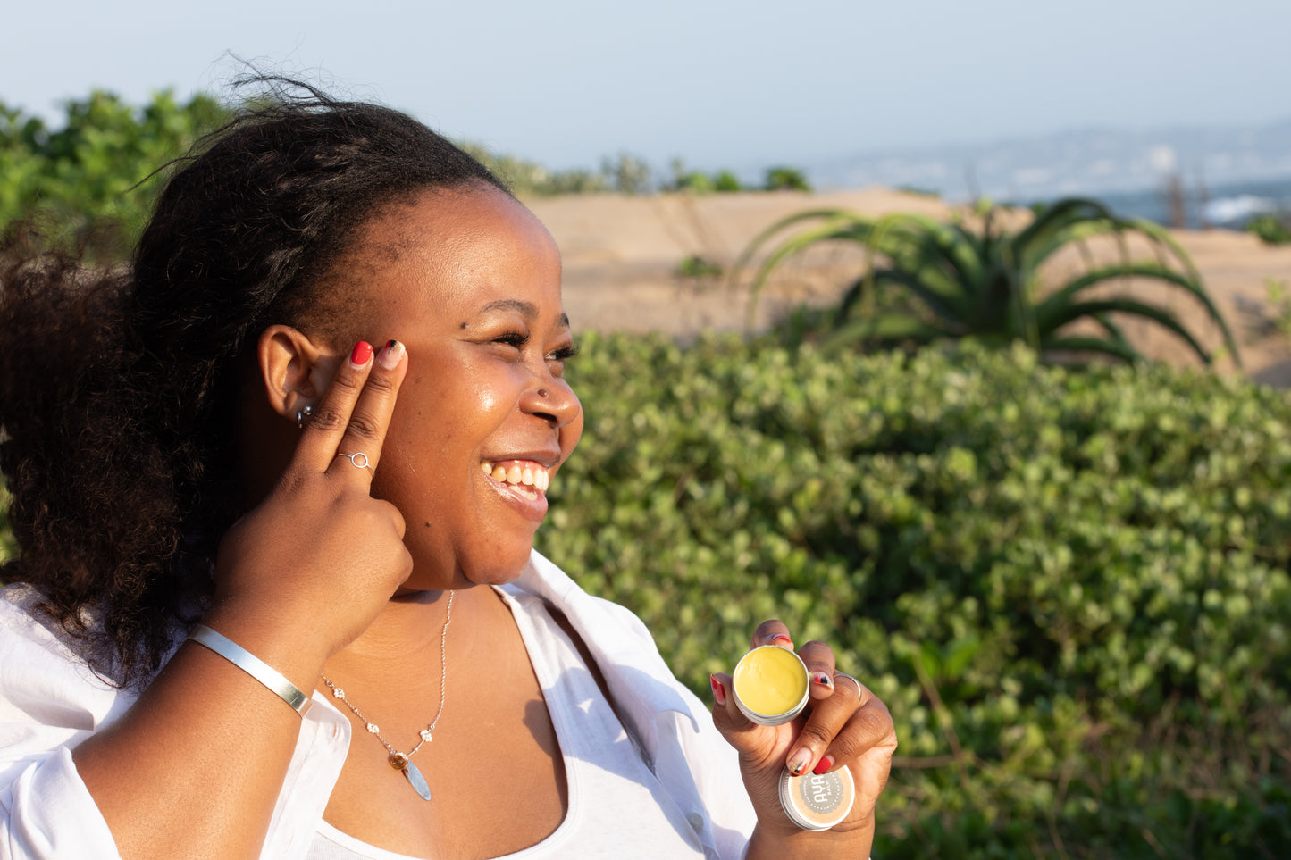 Woman applying AYA Balm natural fermented papaya balm outdoors, South Africa skincare