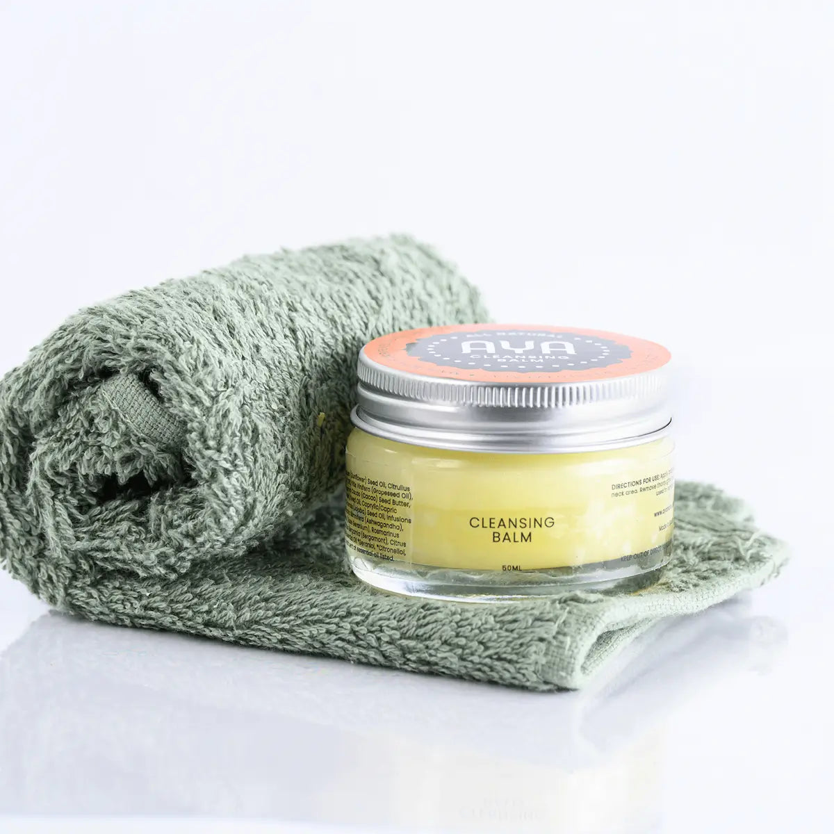 AYA Cleansing Balm 50ml glass jar with natural ingredients on sage green face cloth